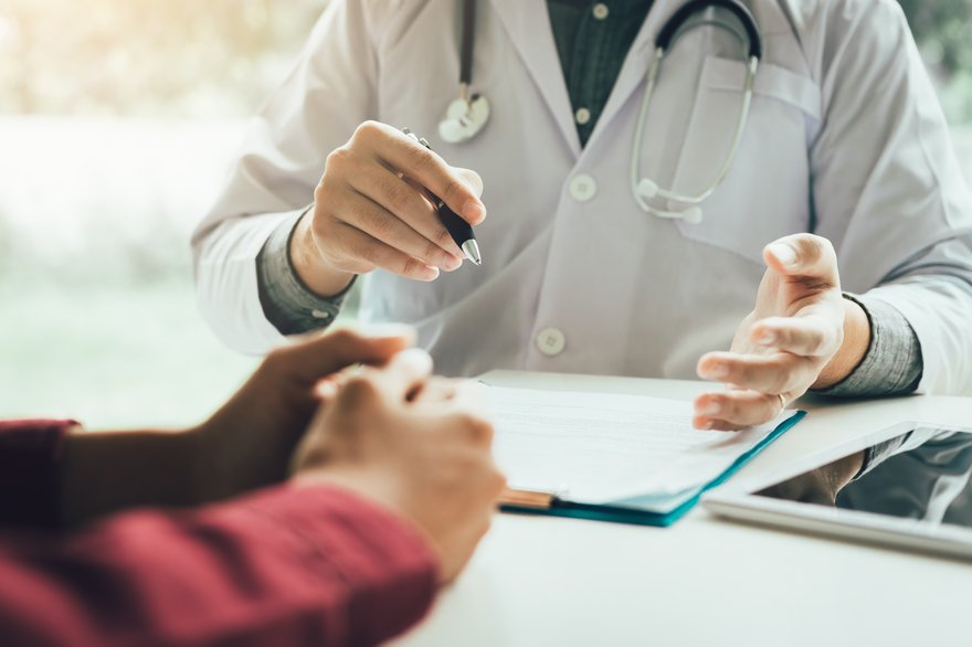 Doctor with a chart in from of him sits across from an individual.