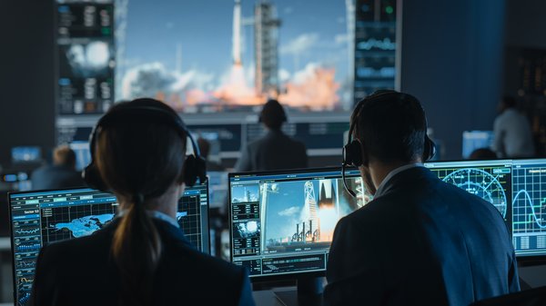 Group of people in mission control center witness successful space rocket launch.