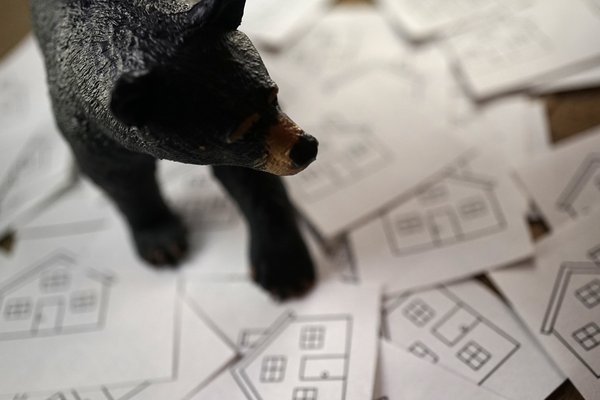 Bear figure on top of cards with houses stenciled on them.
