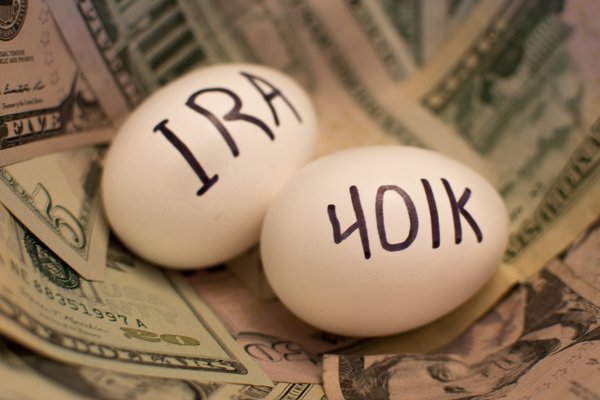 Two eggs sitting on a pile of cash, one labeled IRA and the other 401k.