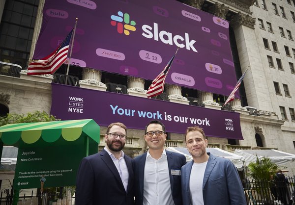Slack CTO, CFO, and CEO in front of the New York Stock Exchange with a banner announcing the company's IPO.