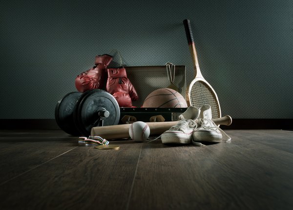 A variety of sporting equipment on the floor in a darkened room.
