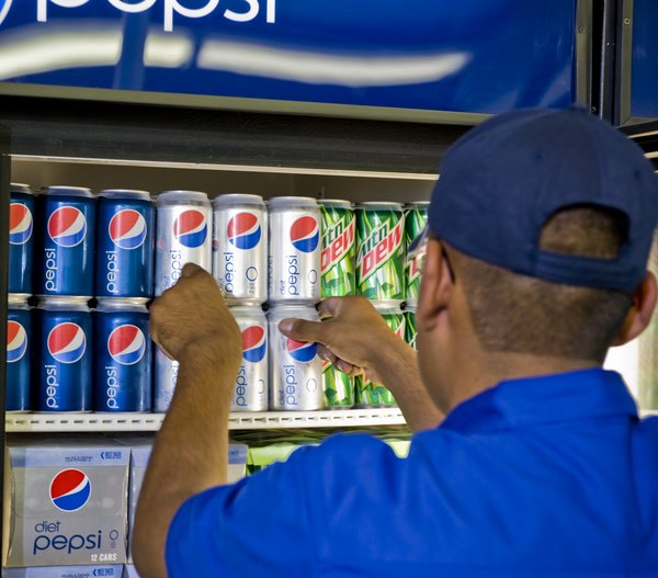 A worker fills a refrigerator with Pepsi products.