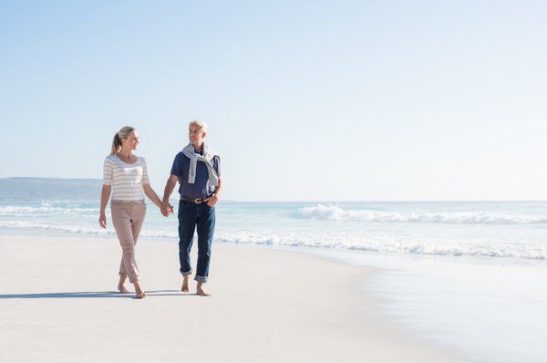 An older couple walks on a beach