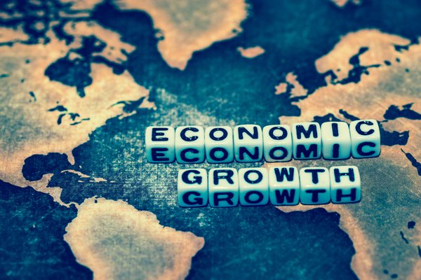 Lettered die spelling economic growth sitting atop a faded world map.