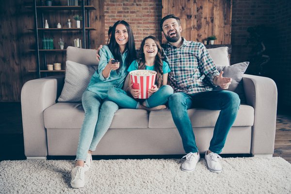 Happy family on couch eating popcorn while watching TV
