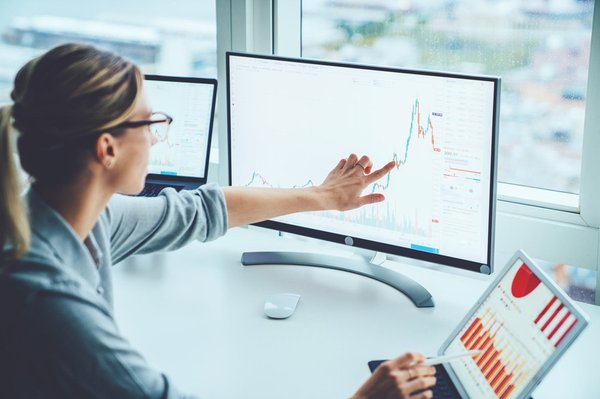 Woman looking at a stock chart on a monitor.