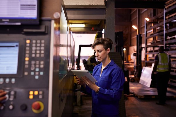 Someone in a manufacturing facility holding a tablet.