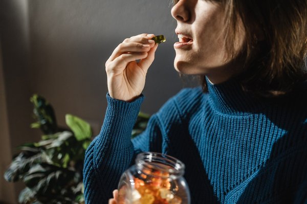 woman holding gummy bear edible an inch from her mouth