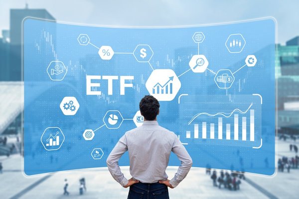 A person looking at a screen with the word ETF on it along with several investing diagrams.