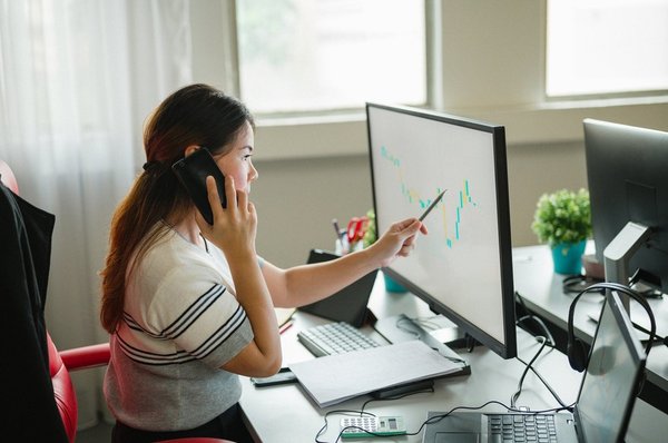 A woman tracking stock prices on a computer screen.