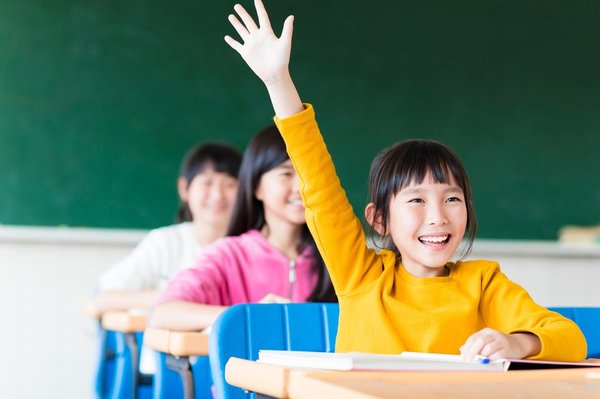 A child raises her hand while learning in school.