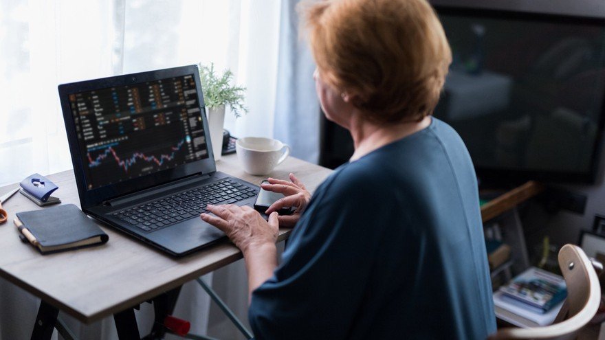 Mature woman looks at stocks on laptop