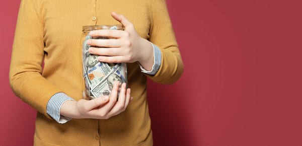 A person holding a jar of money.