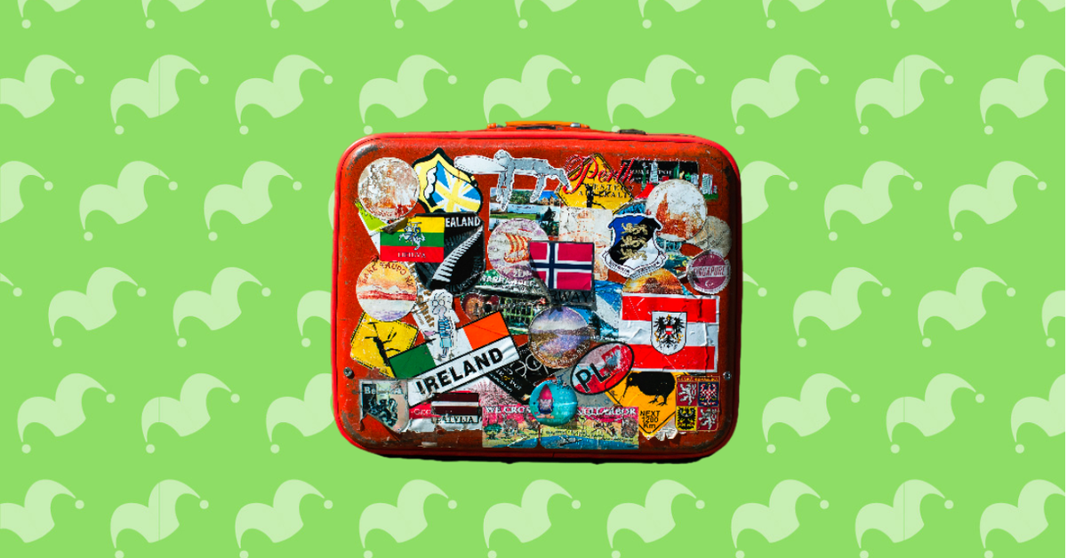 A suitcase covered in stickers against a green background