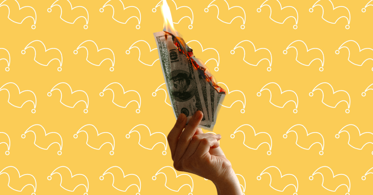 A hand holding four hundred dollar bills that are on fire