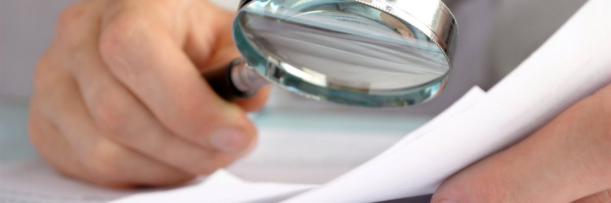 A magnifying glass being held over some paperwork.
