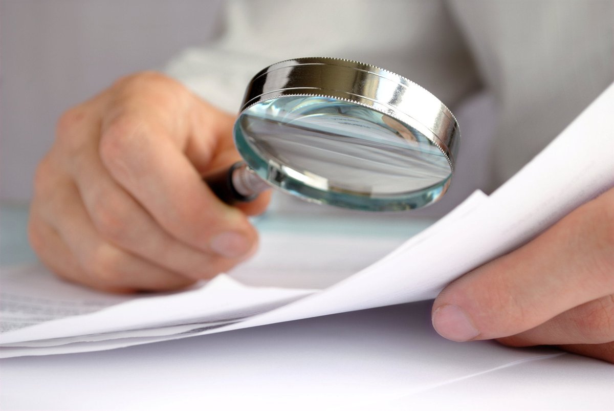 A magnifying glass being held over some paperwork.