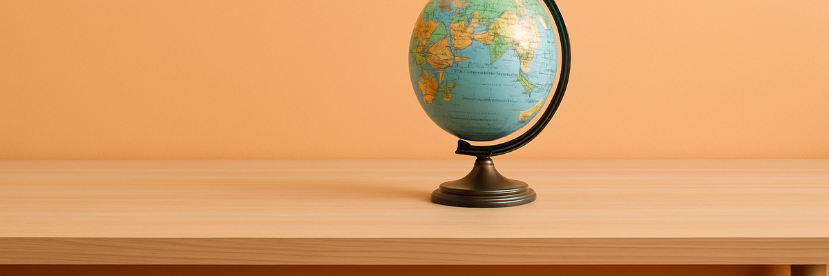 A globe on a globe stand atop a desk.