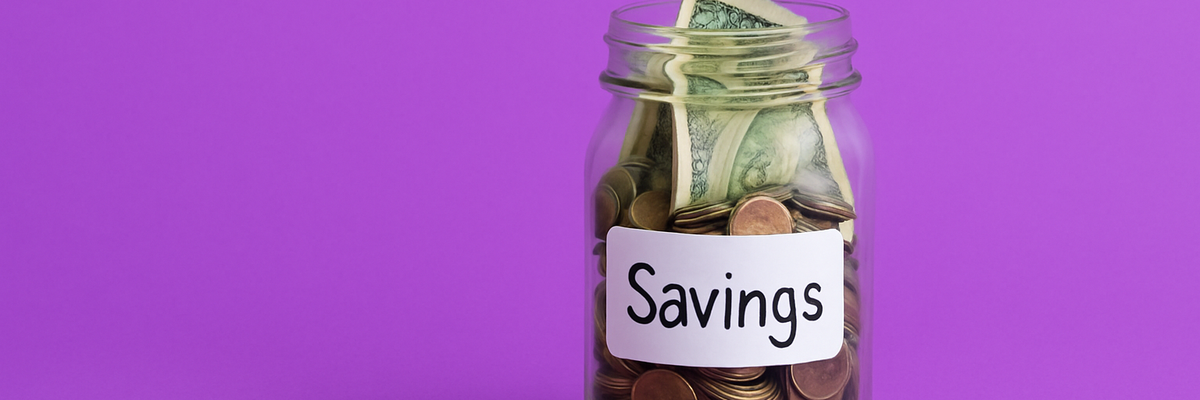 A glass jar labeled "Savings" that's full of coins and bills.