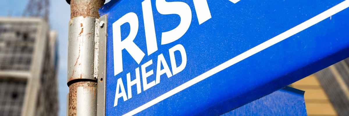 A blue street sign reading Risk Ahead.