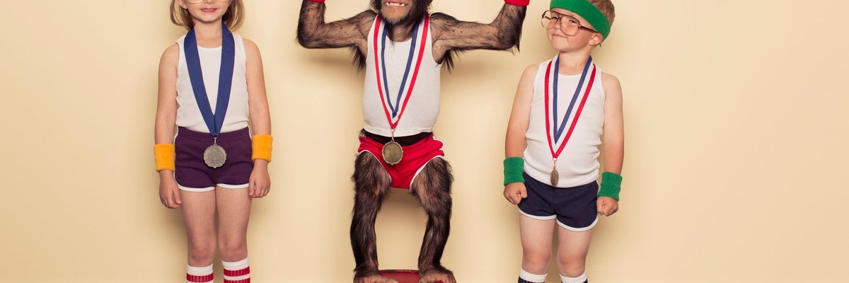 A chimpanzee poses with children at medal podium.