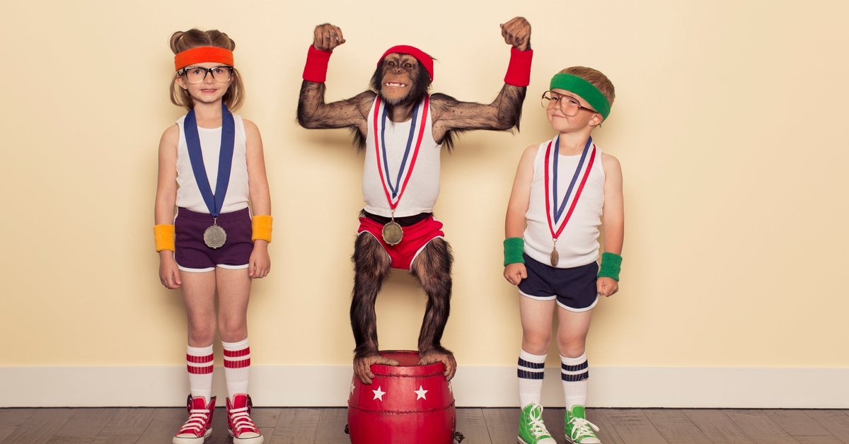 A chimpanzee poses with children at medal podium.
