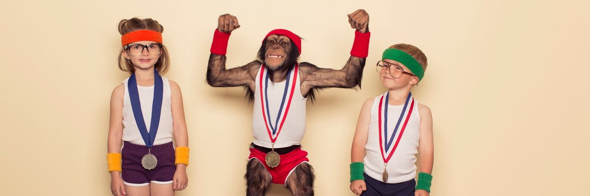 A chimpanzee poses with children at medal podium.