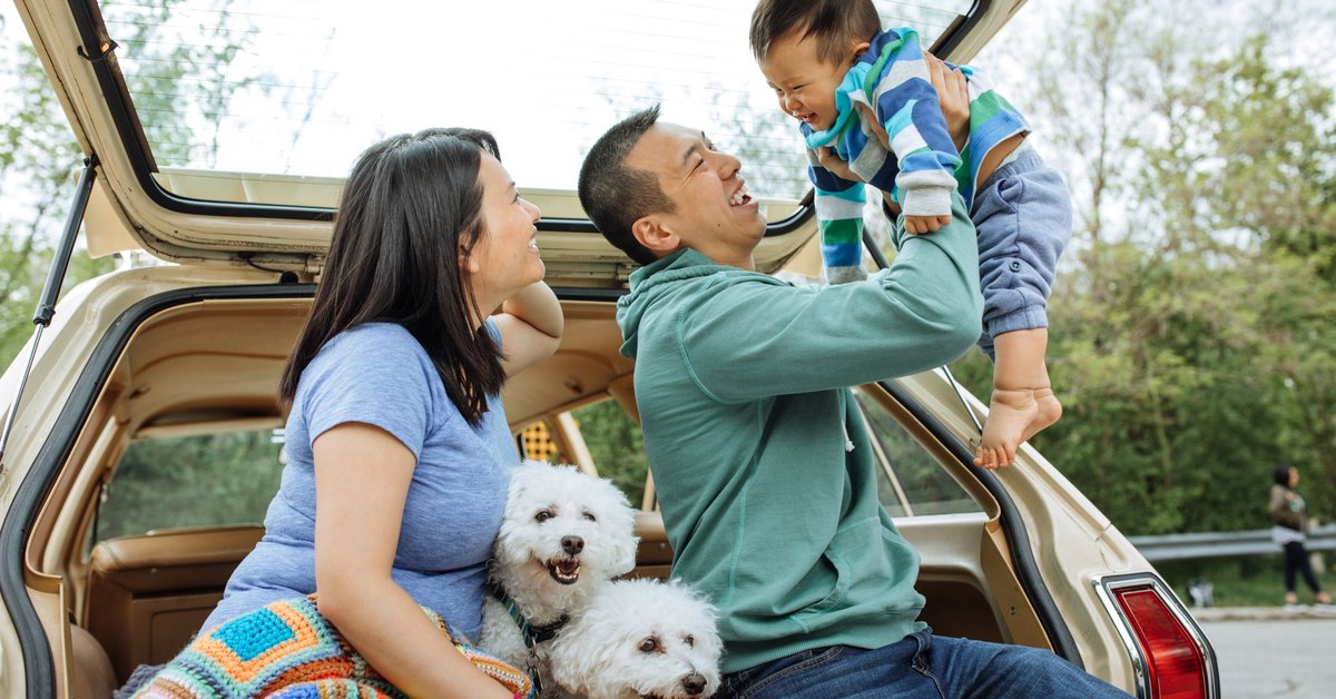 A couple smile and enjoy the day with their baby and two dogs.