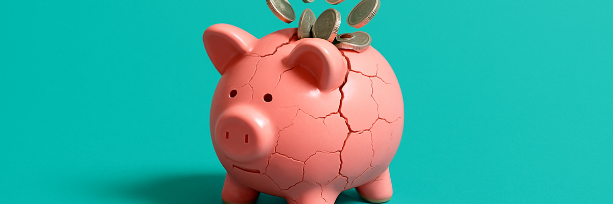 A piggy bank is full to bursting and is beginning to crack and spill coins.