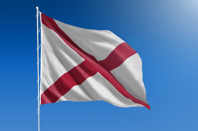 The Alabama state flag in front of a blue sky.