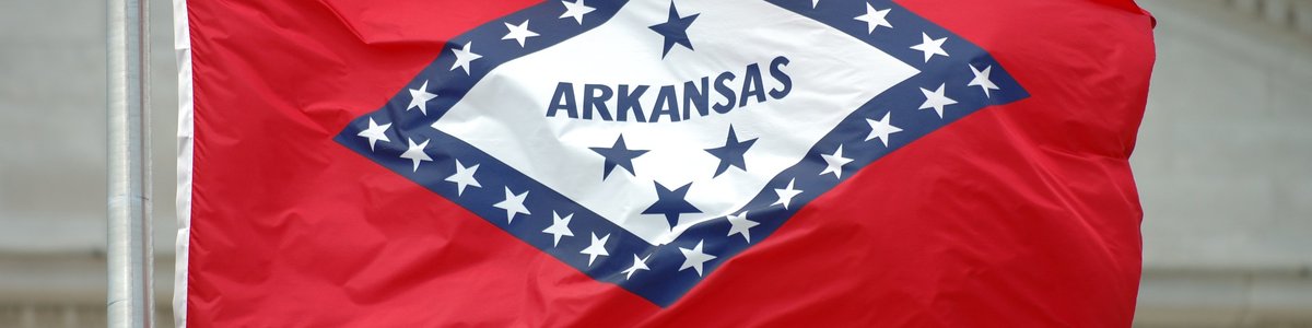 The Arkansas state flag flying in front of a courthouse.
