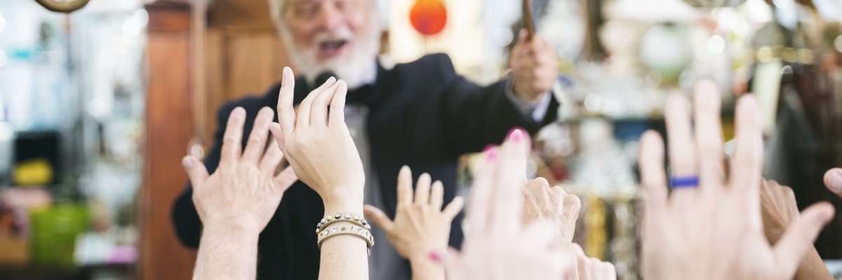 Auctioneer at the head of an auction house crowd of buyers.