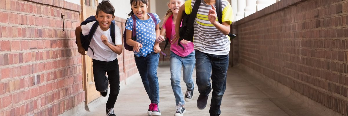 Cute pupils running down the hall in school.