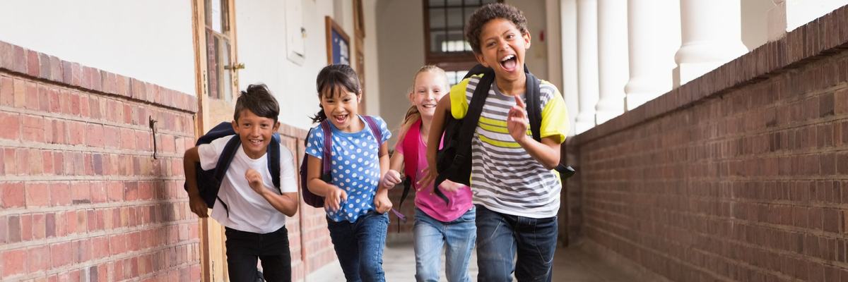 Cute pupils running down the hall in school.