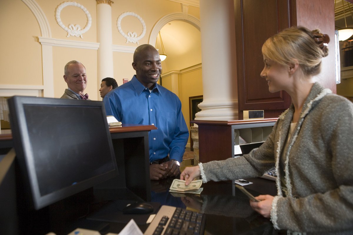 Man at bank smiling as teller hands him cash.