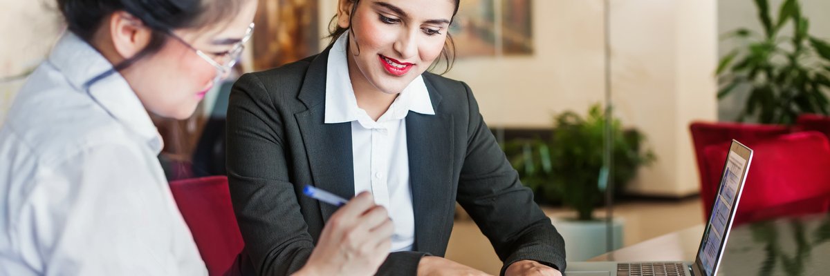 A bank employee showing a customer where to sign documents.