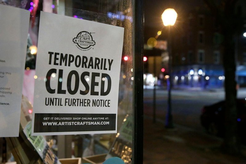 A sign in an art shop window advises customers that the store is temporarily closed, and that customers can shop for delivery online.