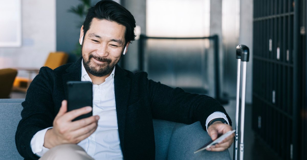 A man smiles as he looks at his phone.