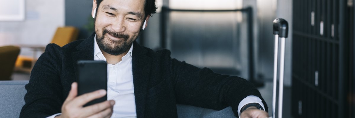 A man smiles as he looks at his phone.