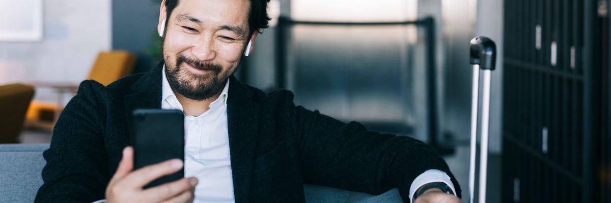 A man smiles as he looks at his phone.