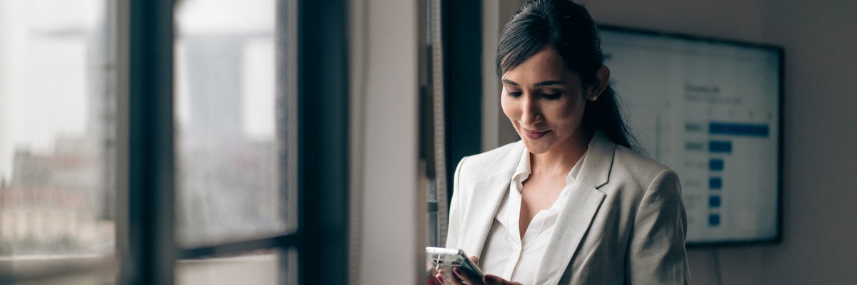 A businesswoman is at the office, on her phone.