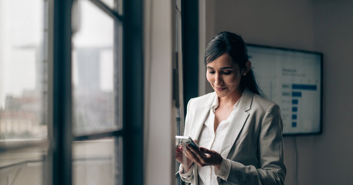 A businesswoman is at the office, on her phone.