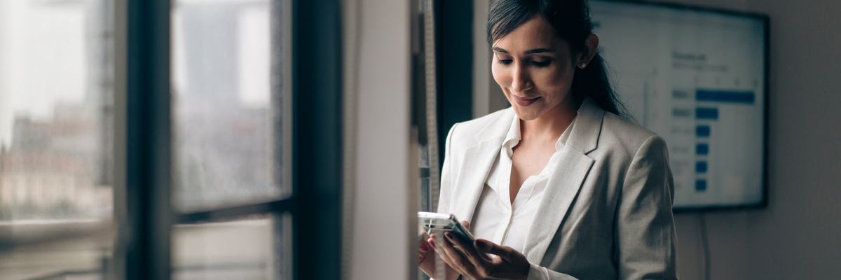 A businesswoman is at the office, on her phone.