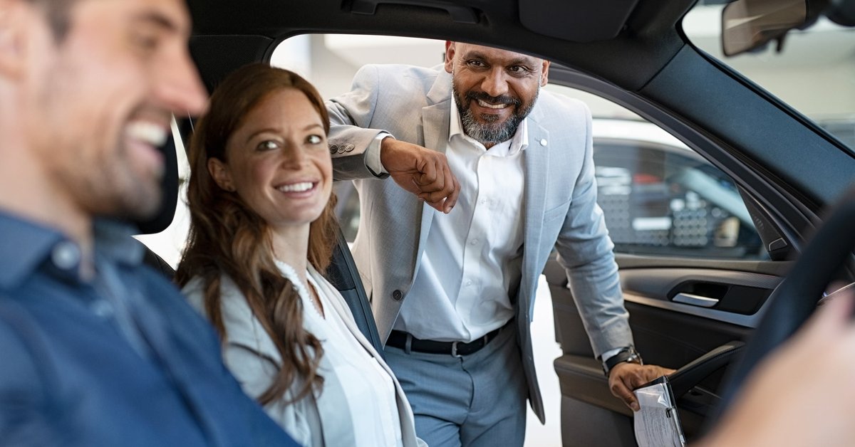Car salesman assisting couple with car purchase.