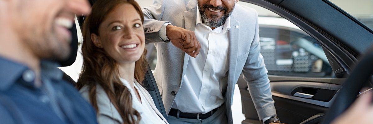 Car salesman assisting couple with car purchase.