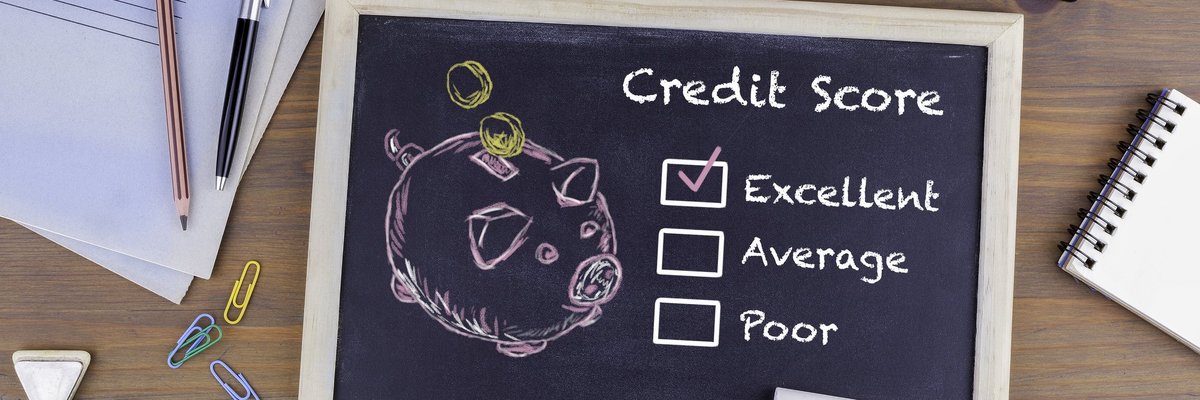 A desk with a chalkboard with drawing of a piggy bank and a checkmark next to Excellent Credit Score.