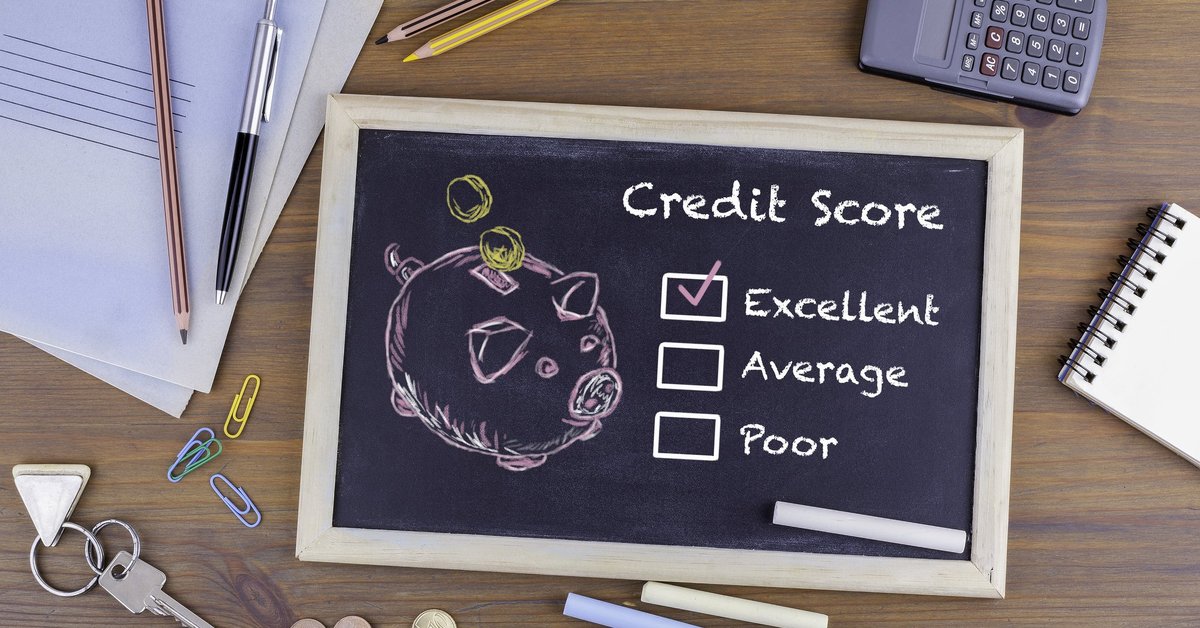 A desk with a chalkboard with drawing of a piggy bank and a checkmark next to Excellent Credit Score.