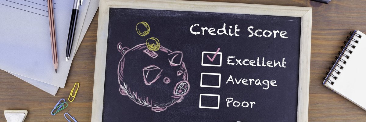 A desk with a chalkboard with drawing of a piggy bank and a checkmark next to Excellent Credit Score.