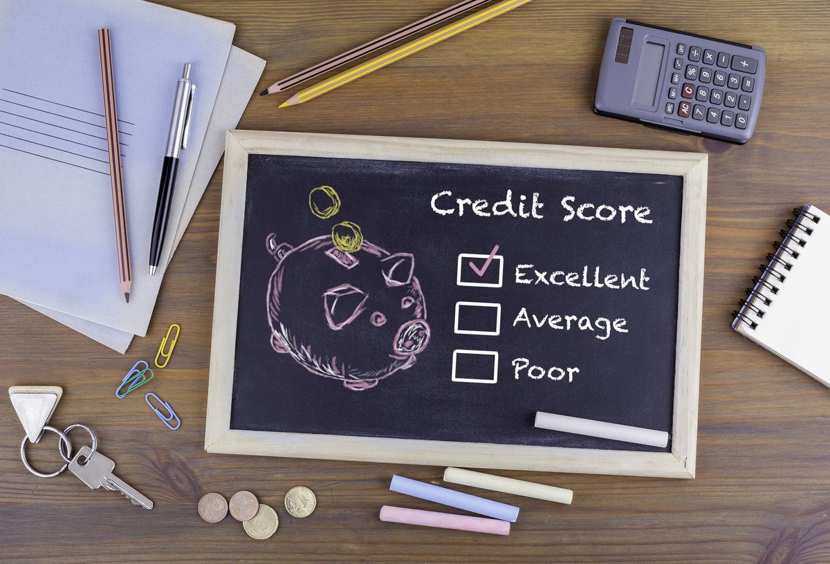A desk with a chalkboard with drawing of a piggy bank and a checkmark next to Excellent Credit Score.